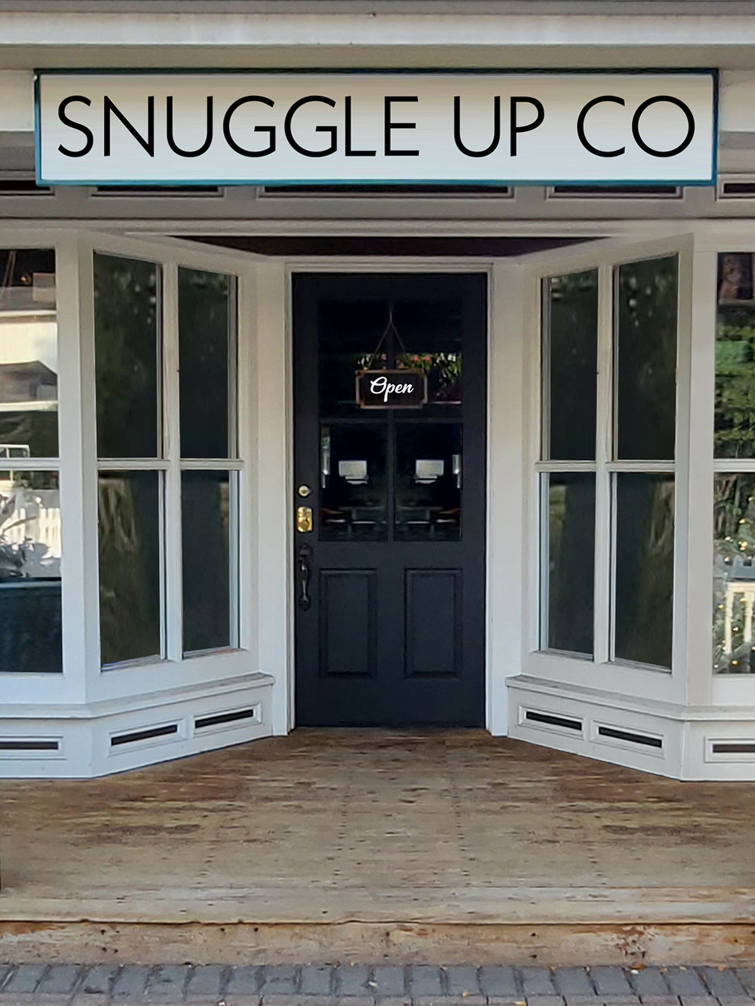 Close up of Snuggle Up Co's shop with an Open Sign on the front door. Picket white fence with a walkway to the shop of Snuggle Up Co