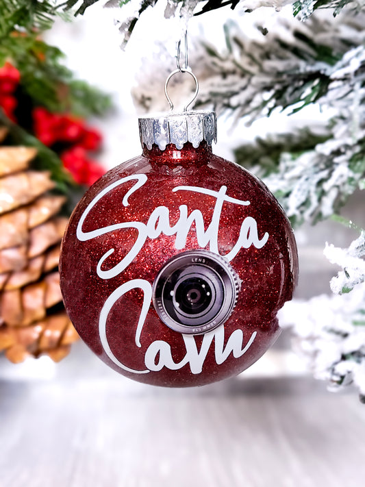 Handcrafted Santa Cam Ornament with a sparkling red finish, faux camera lens, and a letter from Santa Claus, perfect for adding magic to holiday décor.