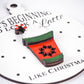 Close-up of a white ornament with the raised design of a red coffee cup, green accents, whipped cream, and a candy cane on top. The text on the ornament reads, "It's Beginning to Look a Latte Like Christmas" with small black dots as snowflakes on a white background.