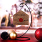 3D wooden envelope ornament addressed to Santa with engraved details, red wax seal, and "Christmas List" text, displayed hanging on a stand with festive background decor. It can hold a small list.