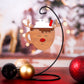 Hanging ornament in the shape of a reindeer mug with whipped cream and a red straw on top, complete with reindeer antlers and a red nose. Displayed on a stand with a festive background.