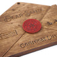 Close-up of a wooden "Dear Santa" envelope ornament with engraved details. Features a red "North Pole Post Office" seal, "Sleigh Mail" stamp, and "Christmas List" text on the bottom.