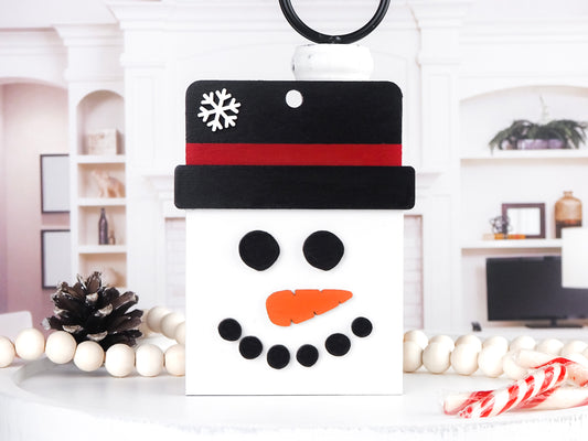 Handcrafted wooden Snowman Gift Card Ornament featuring a jolly snowman face with a black top hat, red band, and carrot nose, perfect for holding gift cards and adding festive charm to holiday décor.