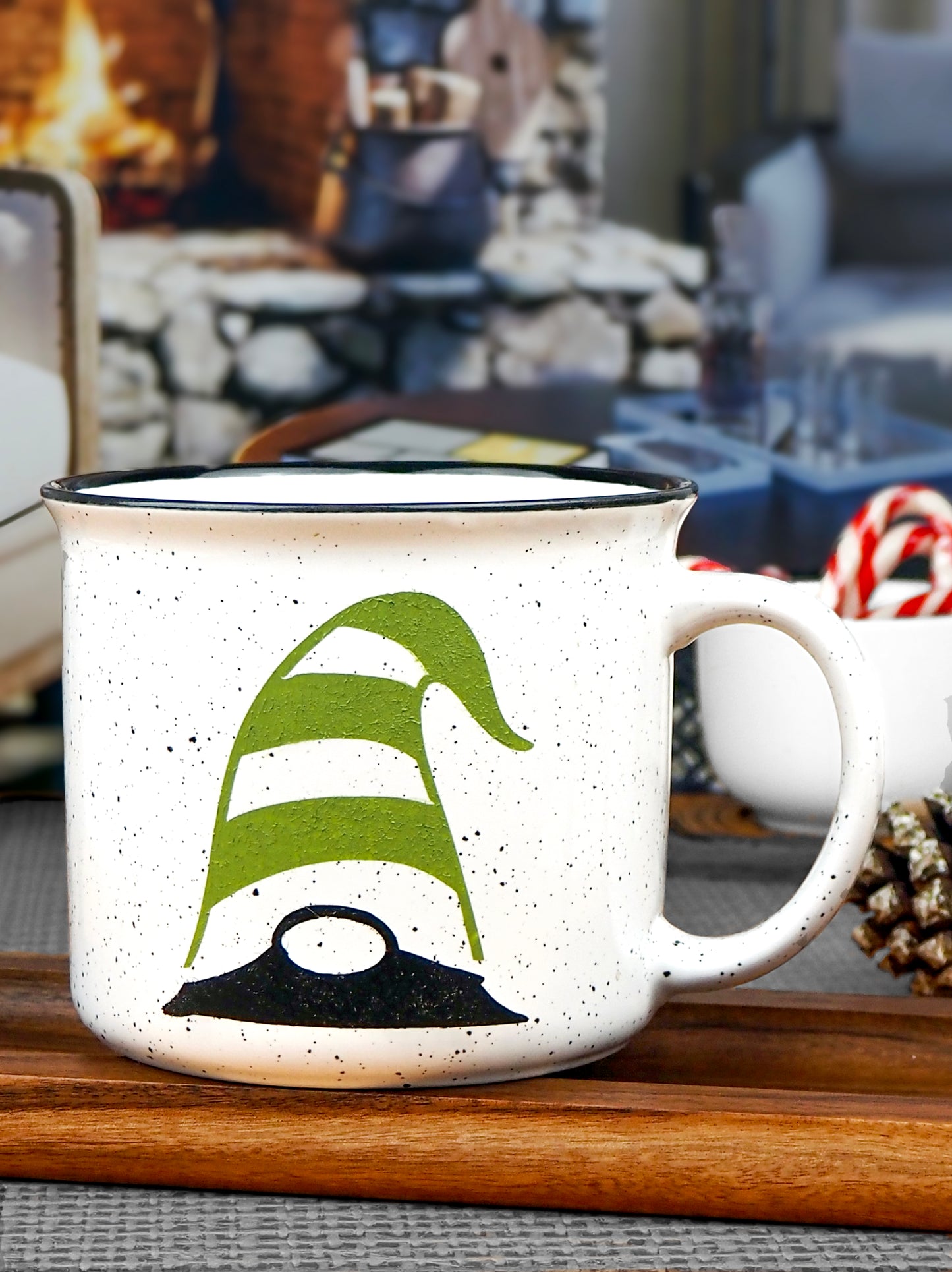 White speckled ceramic campfire mug with a black rim. The mug features a whimsical gnome design, with the gnome wearing a green and white striped hat that covers its eyes, with only the black nose and part of the beard visible.