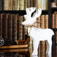 White wooden reindeer with a twine bow around its neck, displayed against a backdrop of vintage books and cozy pinecones.