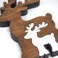 Close-up of a wooden reindeer decoration with a smaller white reindeer shape cut out inside, showcasing the smooth brown finish and layered wood edges against a clean white background.