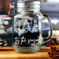 Clear glass mason jar-style mug with a handle. The mug features three white, stylized Christmas trees in a row at the top. Below the trees, the text 'Tis the season is written in a white, flowing script.