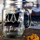 Clear glass mason jar-style mug with a handle. The mug features three white, stylized Christmas trees in a row at the top. Below the trees, the text 'Tis the season is written in a white, flowing script.