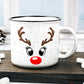 White speckled ceramic campfire mug with a black rim, featuring a reindeer face design. The face includes large black eyes, brown antlers, and a bright red nose, resembling Rudolph the Red-Nosed Reindeer.