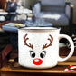 White speckled ceramic campfire mug with a black rim, featuring a reindeer face design. The face includes large black eyes, brown antlers, and a bright red nose, resembling Rudolph the Red-Nosed Reindeer.