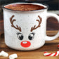 White speckled ceramic campfire mug with a black rim, featuring a reindeer face design. The face includes large black eyes, brown antlers, and a bright red nose, resembling Rudolph the Red-Nosed Reindeer.