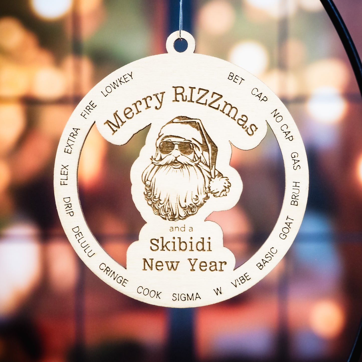 Wooden Christmas ornament engraved with Merry Rizzmas and a Skibidi New Year featuring Santa wearing sunglasses. Trendy slang words are etched around Santa in a circular design. The ornament hangs on a black metal stand with a festive blurred bokeh background of warm holiday lights.