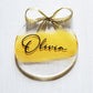 3-inch acrylic discs with gold hand-painted on the back, a personalized name written on the front in black and a gold ribbon tied in a bow. Handmade by Snuggle Up Co.