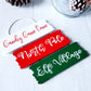 3 wooden hanging décor signs painted each in white, red and green are 2-inches in height and 6.25-inches in length.  Displaying the phrases Candy Cane Lane, North Pole and Elf Village in white. Hand-painted by Snuggle Up Co.