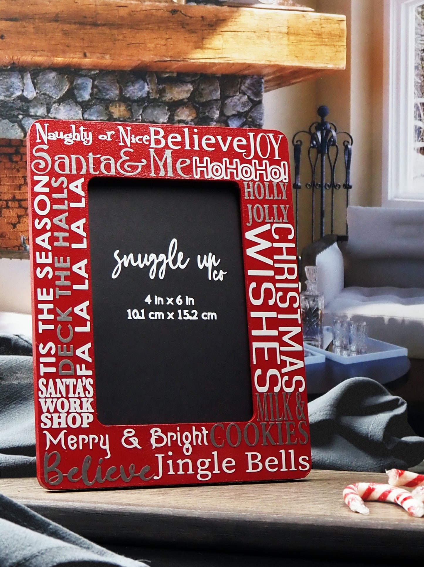 Deep red 4-inch by 6-inch picture frame. In silver and white writing, words are displayed on the frame; Santa & Me, Merry & Bright, Jingle Bells and a few more Christmas phrases. Handmade by Snuggle Up Co