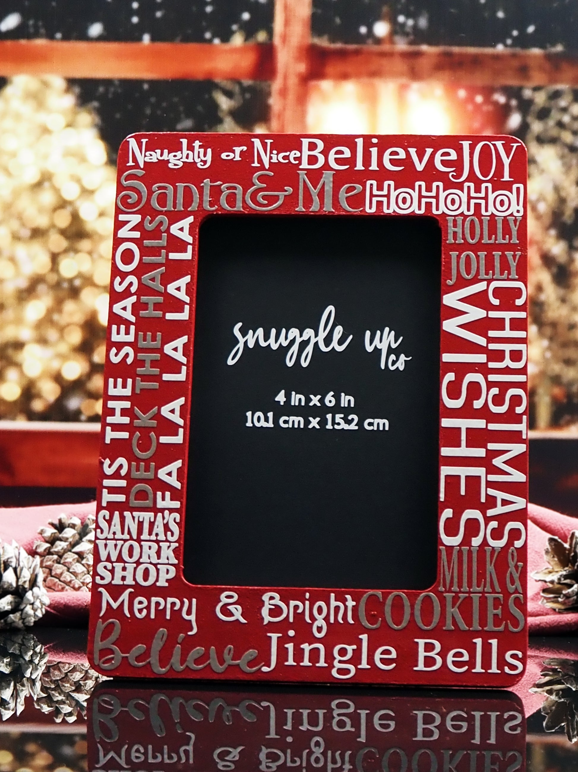 Deep red 4-inch by 6-inch picture frame. In silver and white writing, words are displayed on the frame; Santa & Me, Merry & Bright, Jingle Bells and a few more Christmas phrases. Handmade by Snuggle Up Co