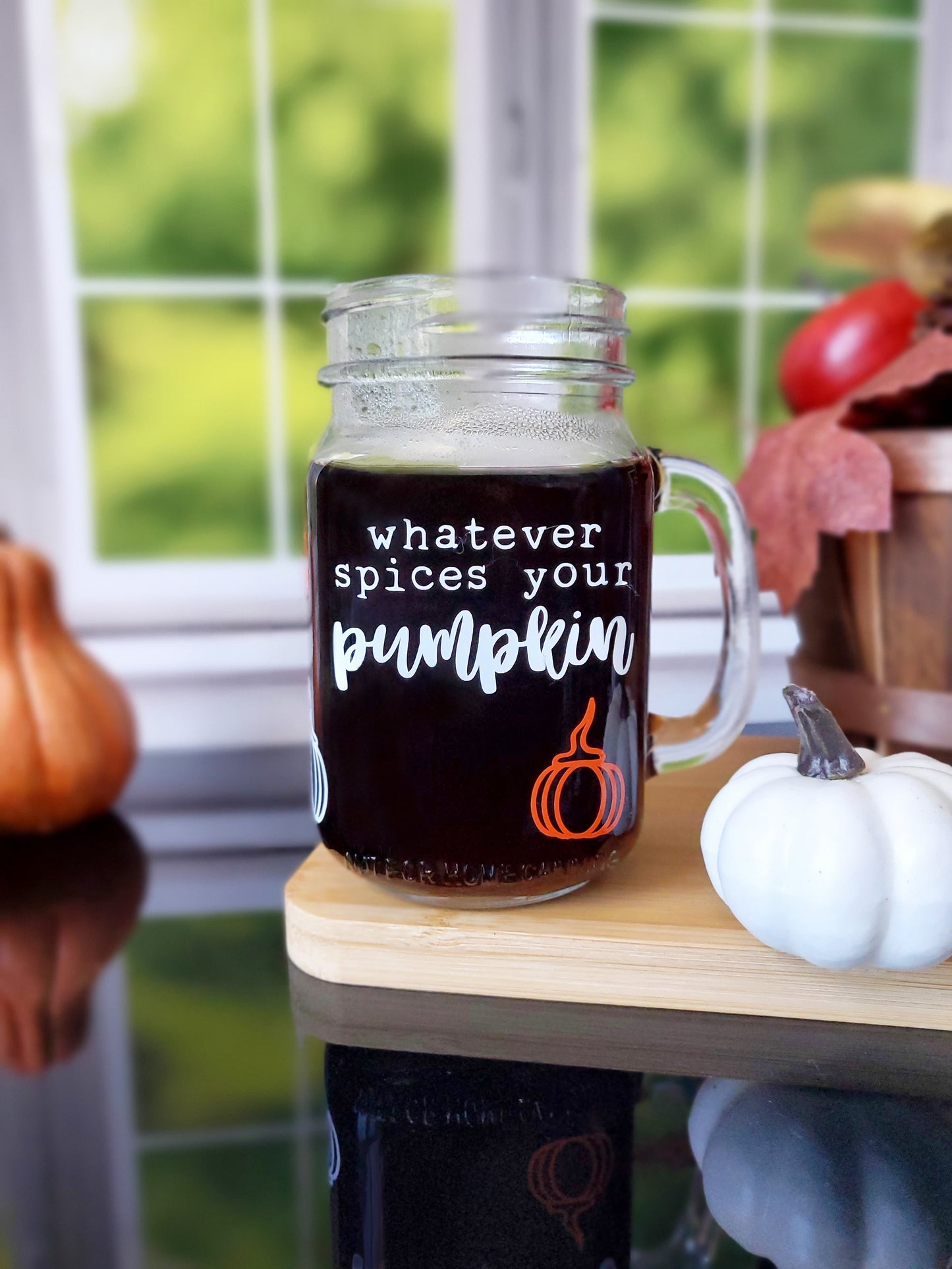 Clear glass mason jar-style mug with a handle. The mug features white text that reads "Whatever spices your pumpkin," along with an orange pumpkin graphic at the bottom.