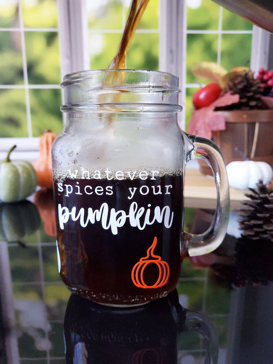 Clear glass mason jar-style mug with a handle. The mug features white text that reads "Whatever spices your pumpkin," along with an orange pumpkin graphic at the bottom.