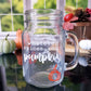 Clear glass mason jar-style mug with a handle. The mug features white text that reads "Whatever spices your pumpkin," along with an orange pumpkin graphic at the bottom.